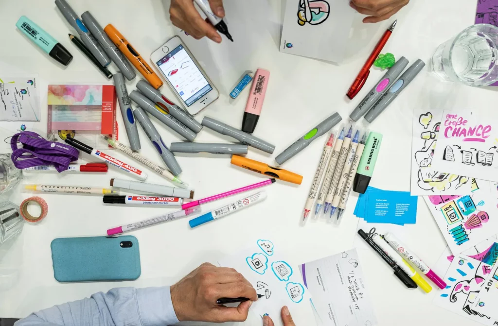 Illustrator zeichnet auf ein Blatt mit vielen Markern und Stiften